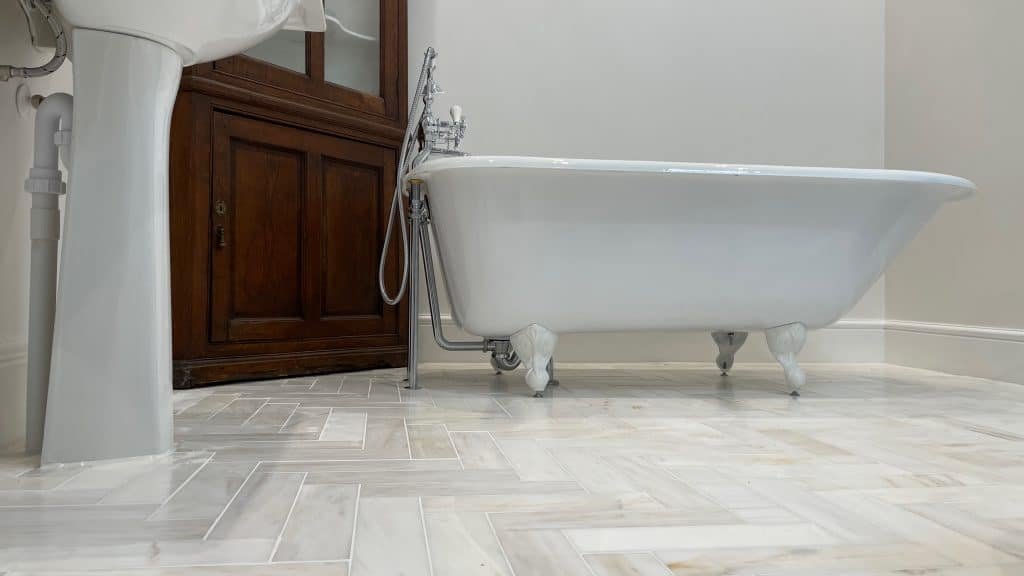 Bathroom in Exeter with roll-top bath and marble herringbone floor tiles