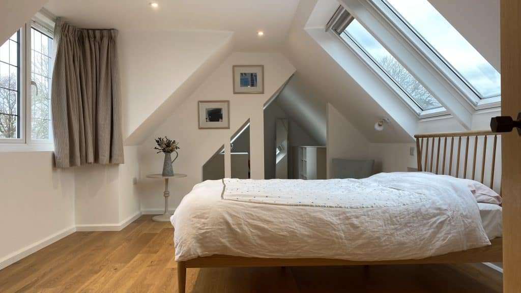 Bed in a loft conversation with roof lights and engineered oak flooring