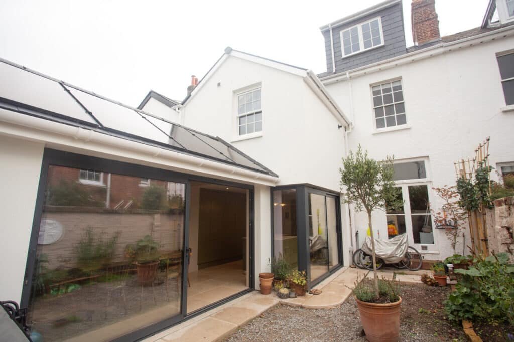 Modern rear house extension with large sliding aluminium doors opening onto courtyard garden.